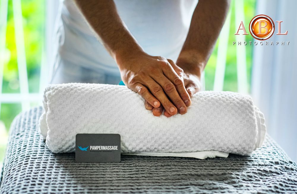 massage table with a towel and therapist's hands on top of the towel